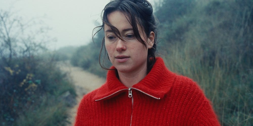 Soft-focused portrait of an artist in a red zip-up sweater outdoors during fall, walking 600 kilometers backwards on the Camino de Santiago.